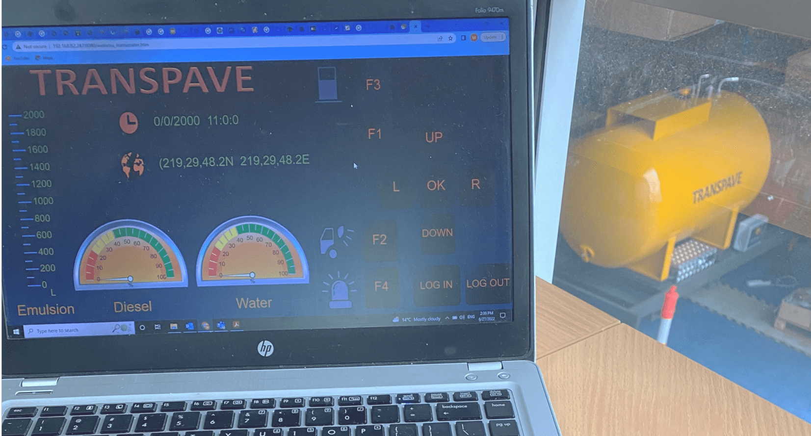 Image of yellow emulsion tank/system in the background, and an open laptop displaying material levels for that system in the foreground.